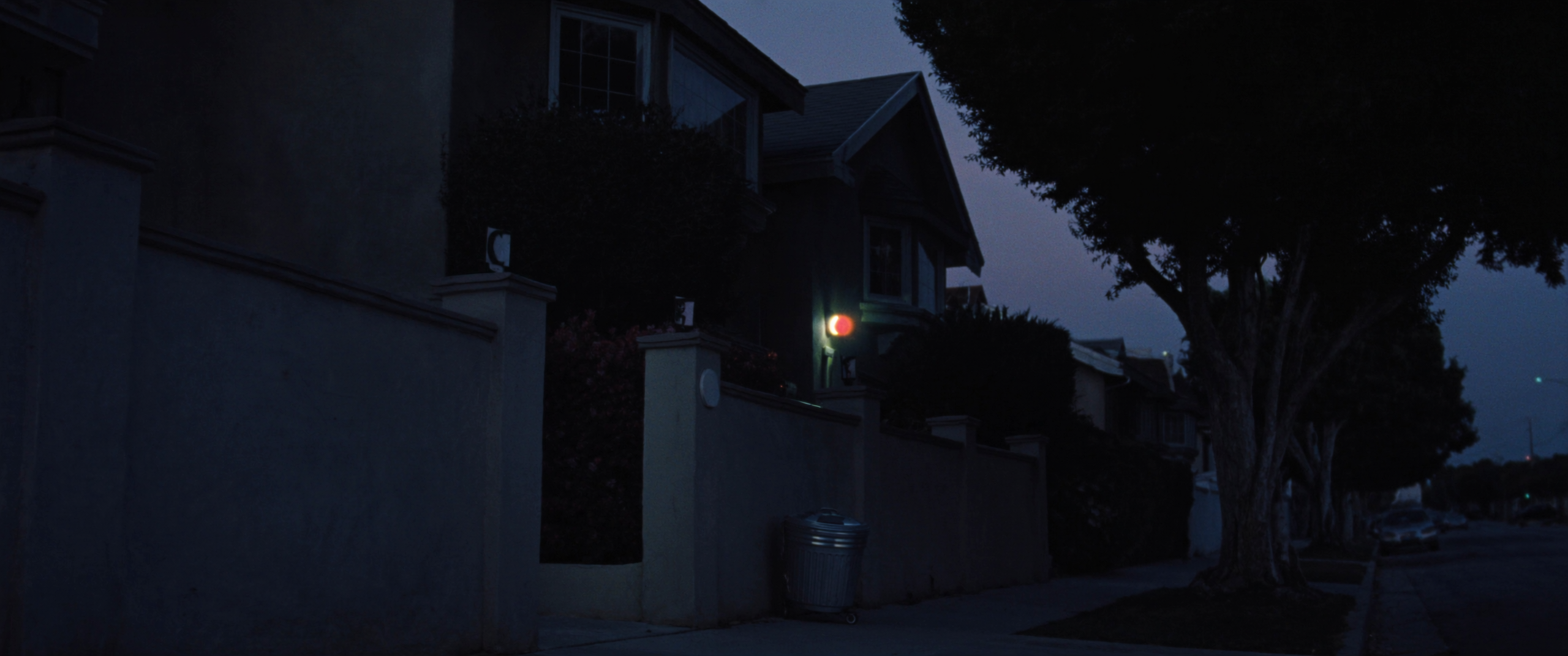 A quiet Orange County residential street at dusk with porch lights coming on