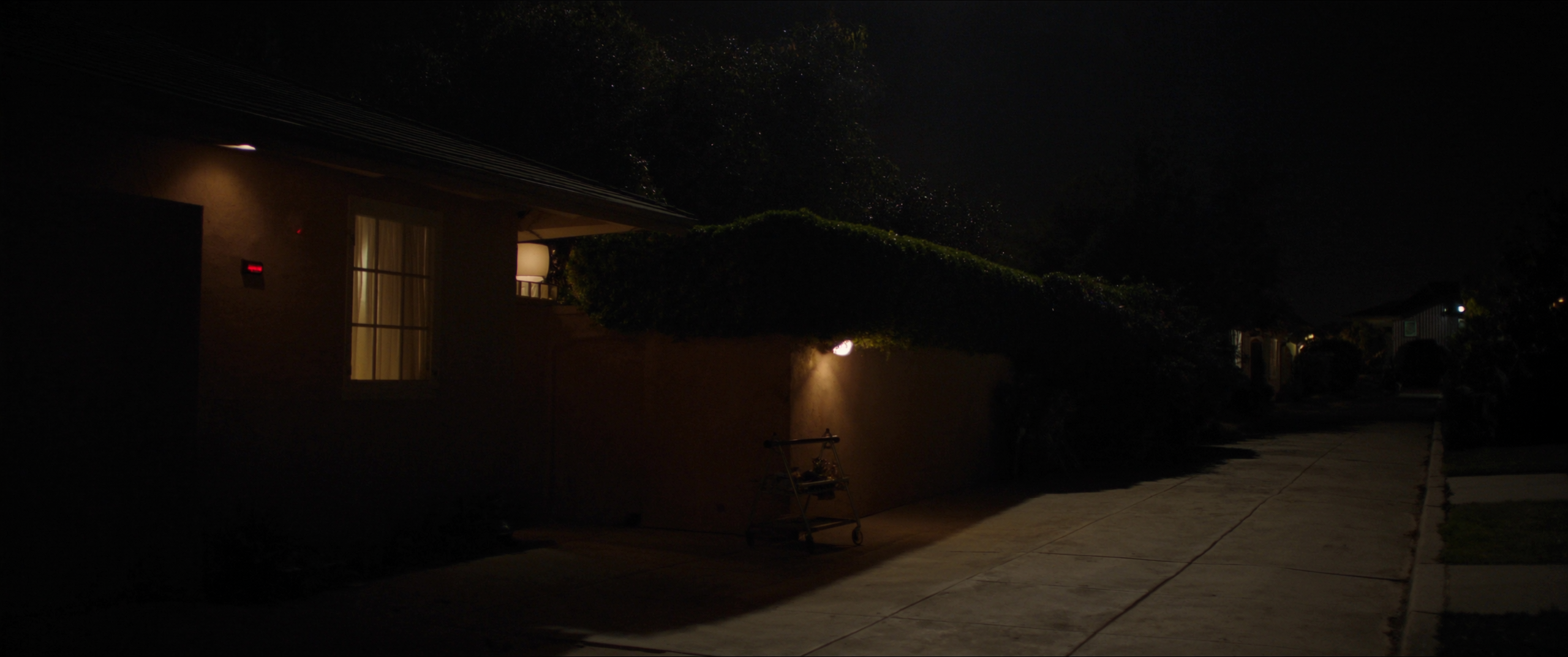 The side of a Southern California home at night, gate closed and a motion light on the path